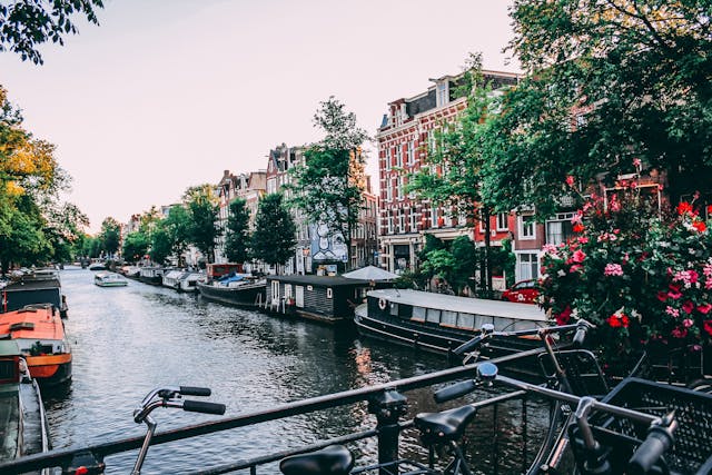 Canales de Ámsterdam con bicicletas y casas flotantes Vista de un canal con casas tradicionales y bicicletas en Ámsterdam