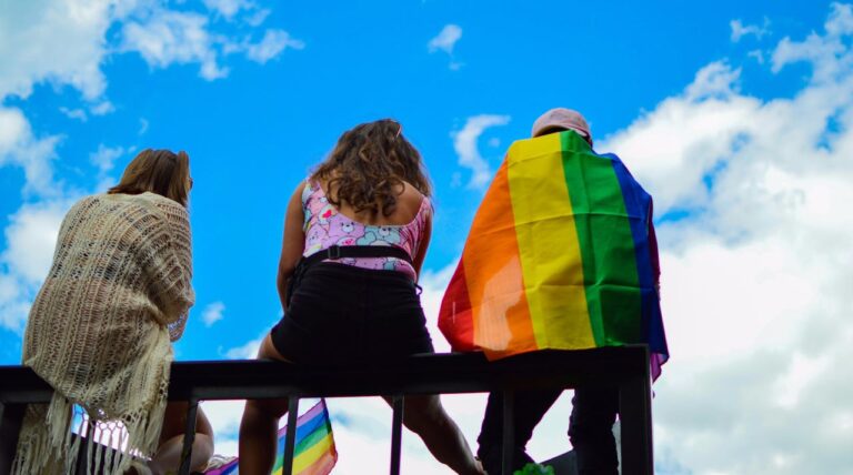 Personas con bandera LGBTQ+ durante un evento al aire libre