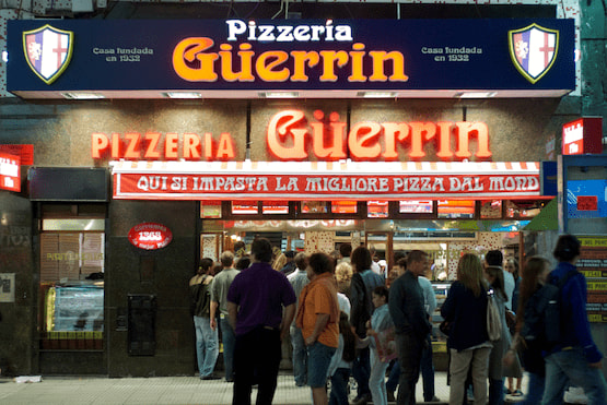 Pizzería Güerrin, ícono de la pizza en Buenos Aires Fachada de la Pizzería Güerrin en la Avenida Corrientes de Buenos Aires con clientes en la entrada