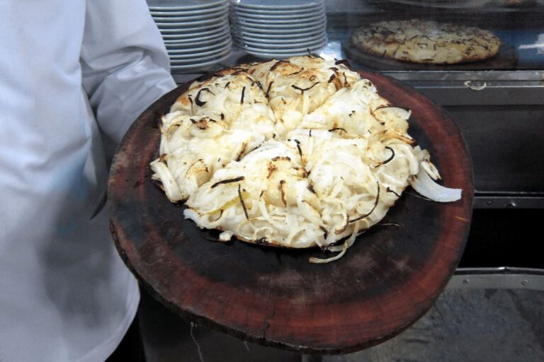 Pizza fugazza argentina con abundante cebolla dorada sobre tabla de madera