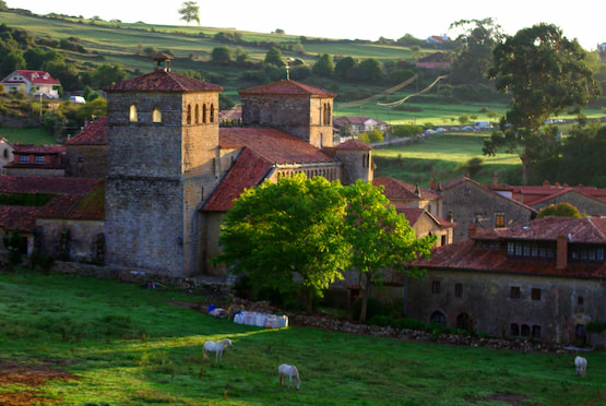 Colegiata de Santa Juliana en Santillana del Mar, Cantabria, rodeada de prados y casas de piedra.