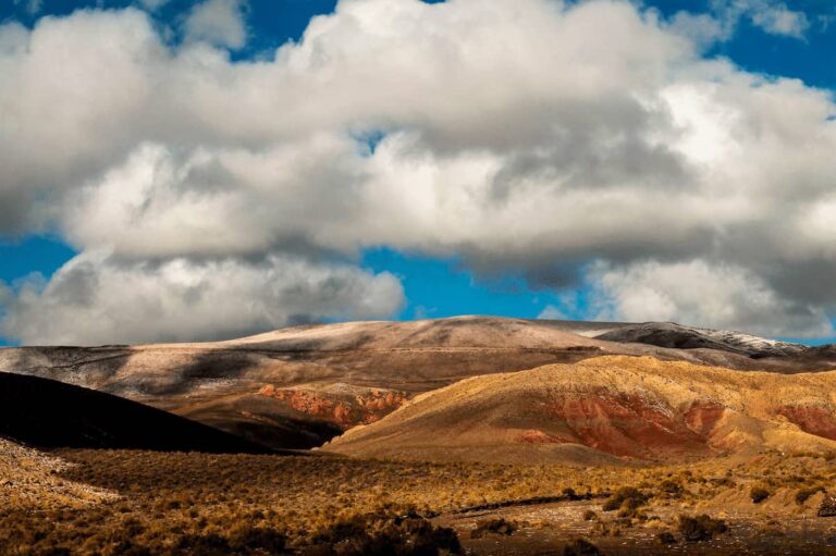 Paisaje de montañas coloridas en los Valles Calchaquíes bajo un cielo con nubes.