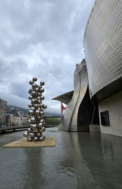 Detalle exterior del Guggenheim de Bilbao con escultura metálica junto al agua.