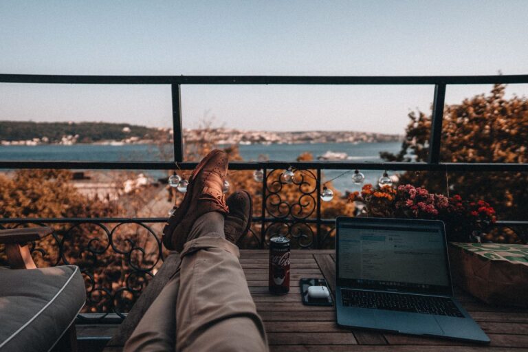 Persona trabajando con una computadora desde un balc&oacute;n durante un viaje, imagen relacionada con una gu&iacute;a sobre qu&eacute; es una Working Holiday Visa.