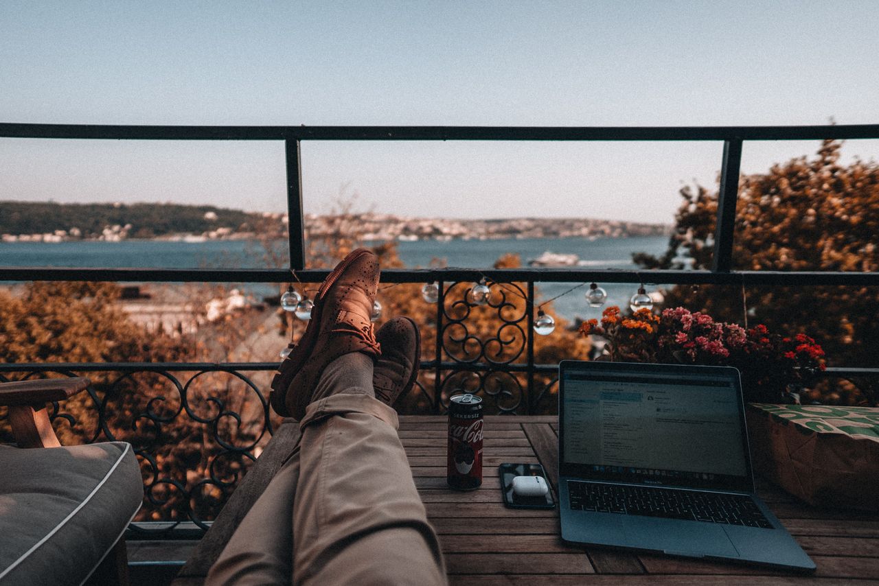 Persona trabajando con una computadora desde un balcón durante un viaje, imagen relacionada con una guía sobre qué es una Working Holiday Visa.