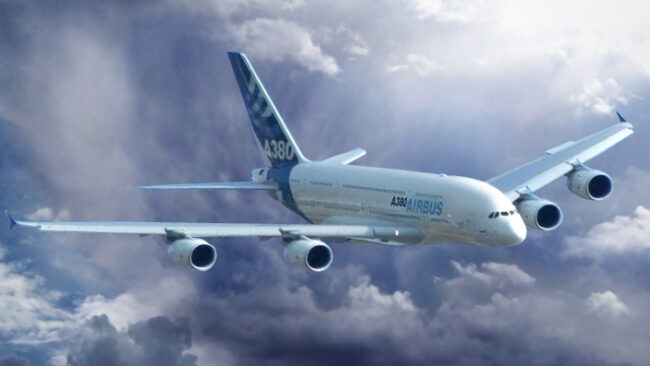 Avión Airbus A380 volando entre nubes en un cielo dramático.

