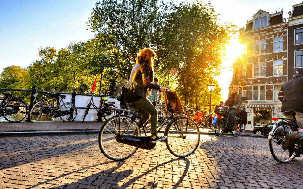 una mujer cruza por un canal de amsterdam en bicicleta