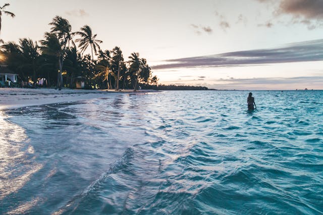 Persona disfrutando del atardecer en las aguas turquesa de una playa de Punta Cana