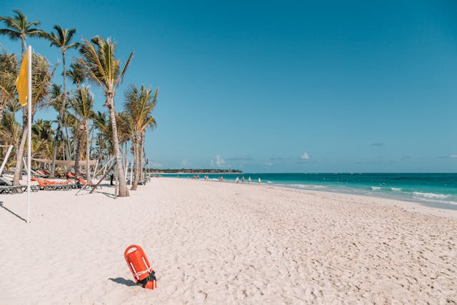 Qué hacer en Punta Cana: disfrutar un día de playa perfecta Vista de una playa en Punta Cana con palmeras, tumbonas y mar turquesa bajo el sol