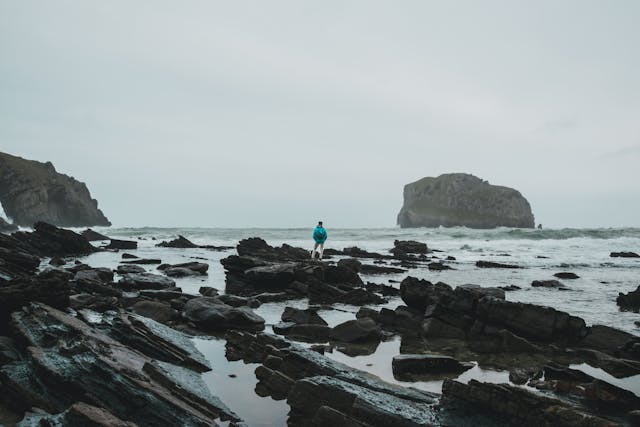 Persona frente al mar Cantábrico con vista al islote de San Juan de Gaztelugatxe, en la costa del País Vasco.