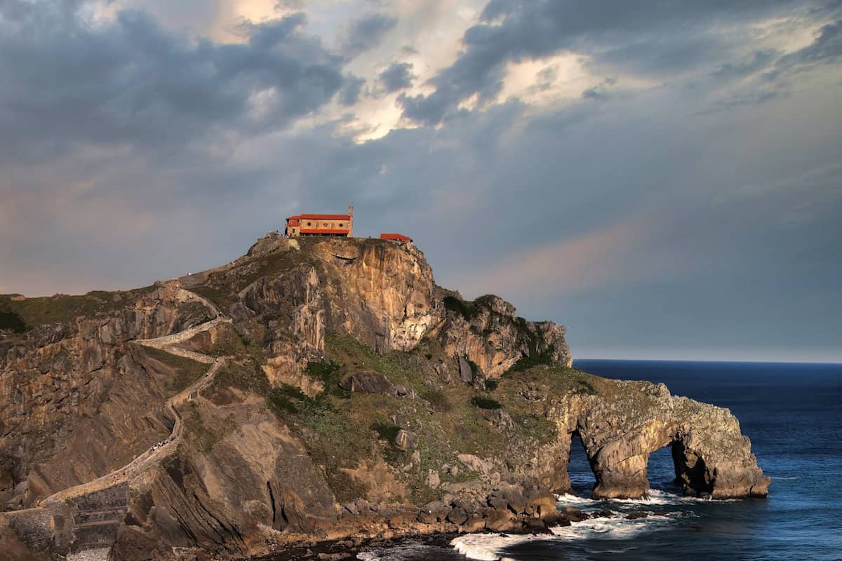 Ermita de San Juan de Gaztelugatxe sobre el acantilado frente al mar Cantábrico, al atardecer.
