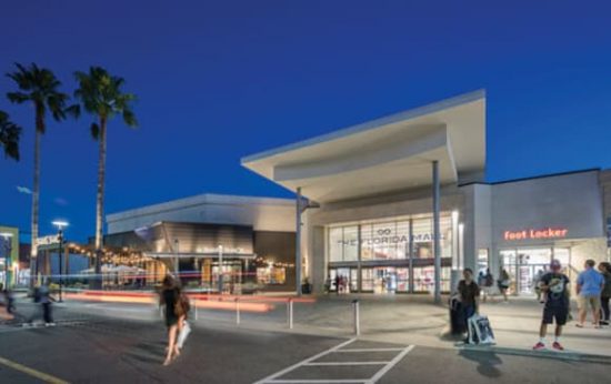 Entrada iluminada de The Florida Mall en Orlando con turistas de compras