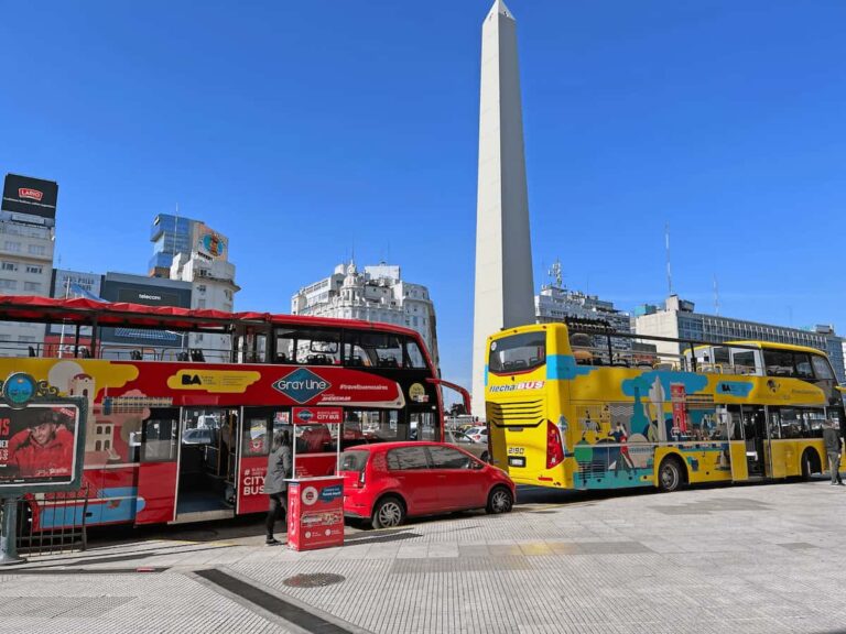 Buses turísticos frente al Obelisco de Buenos Aires en un día soleado