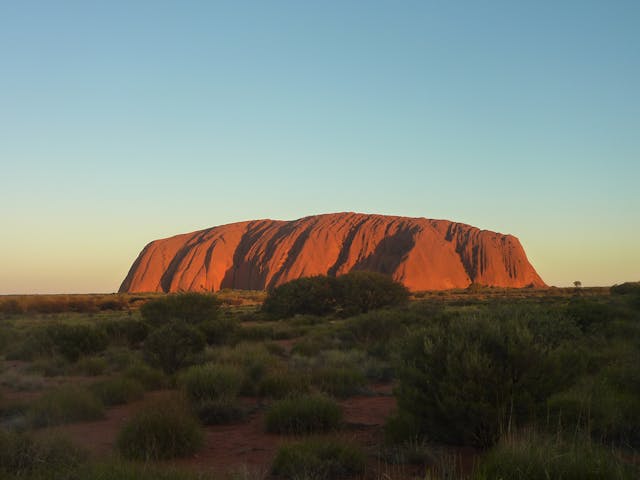 Uluru al atardecer en el corazón del desierto australiano, uno de los lugares sagrados más emblemáticos de Australia.