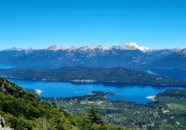 Pequeñas playas de arena al borde del lago, ideales para disfrutar del verano patagónico. Vista panorámica de los lagos y montañas de Villa La Angostura en verano