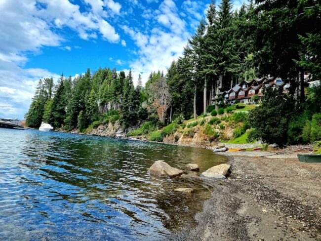 Costa rocosa del lago Nahuel Huapi en Villa La Angostura con bosque y cielo azul