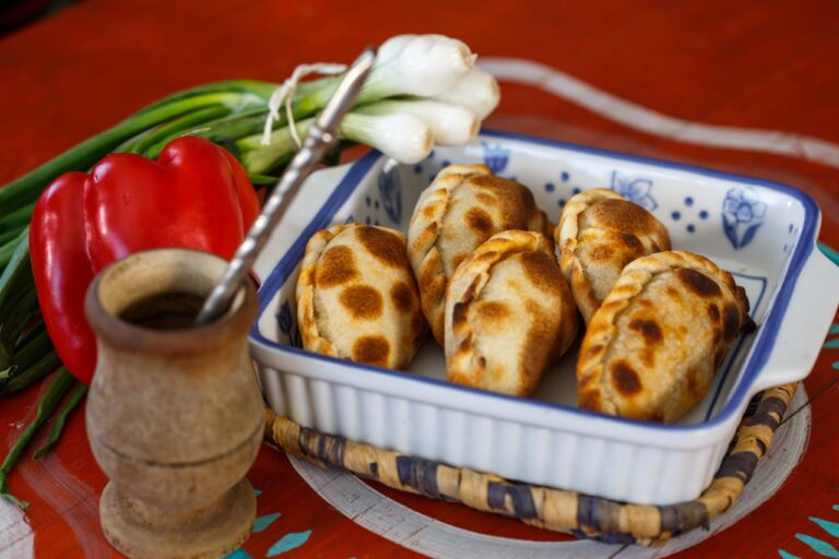 Empanadas argentinas caseras servidas con mate, cebolla de verdeo y pimiento rojo
