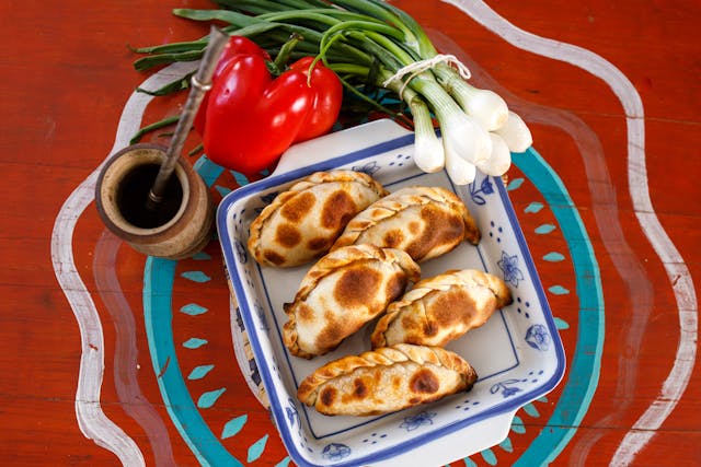 Empanadas argentinas caseras en fuente con mate y vegetales frescos