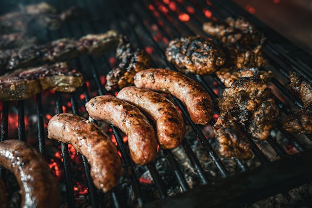 Chorizos y achuras cocinándose en una parrilla argentina sobre brasas