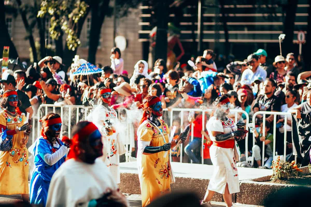 Desfile del Día de los Muertos en México con mujeres maquilladas y vestidas con trajes tradicionales