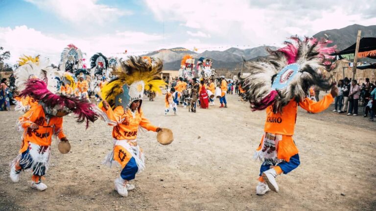 Niños bailando con tocados de plumas en una celebración folclórica andina al aire libre