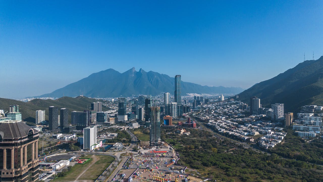 Vista panorámica de Monterrey rodeada de montañas, con edificios modernos, zonas residenciales y paisajes naturales que muestran el contraste urbano y serrano de la ciudad.