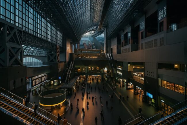 Interior moderno de la estación de Kyoto, con estructura de acero y vidrio y escaleras mecánicas iluminadas.