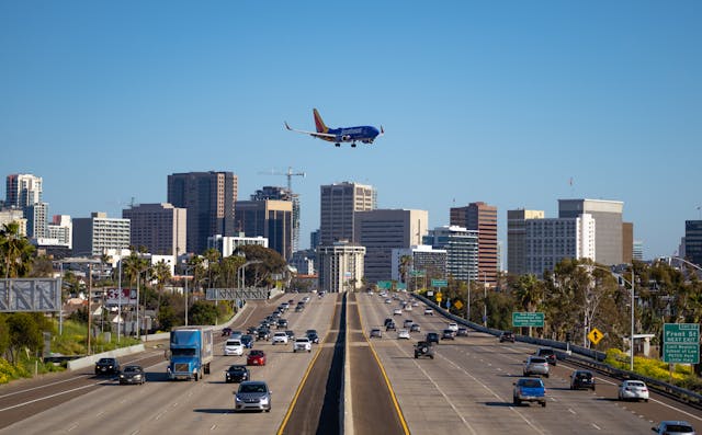 Avión aterrizando sobre la autopista frente al skyline de San Diego