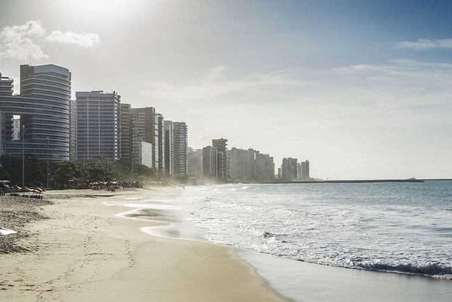 Playa urbana con altos edificios modernos al amanecer en una ciudad costera.