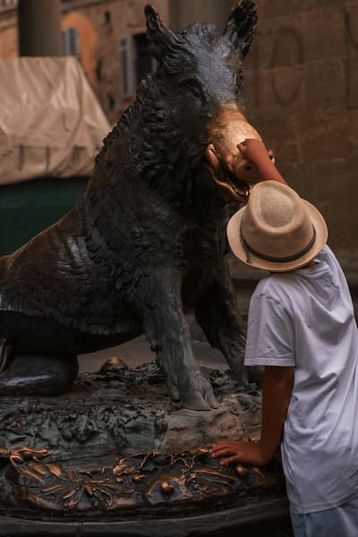 niño toca el hocico del porcellino para tener buena suerte