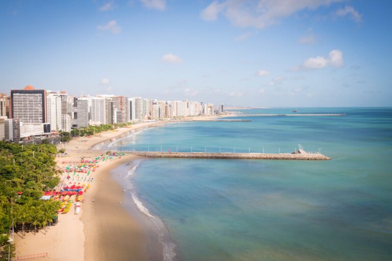 Vista aérea de la playa de Meireles en Fortaleza, Brasil, con rascacielos y sombrillas de colores.