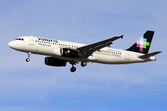Avión de Volaris en pleno vuelo con cielo despejado de fondo.