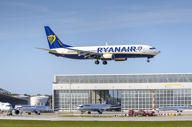 Avión de Ryanair aterrizando en un aeropuerto europeo con hangares de Lufthansa al fondo.