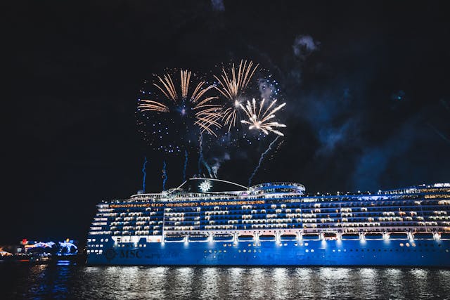 crucero de lujo iluminado de noche con fuegos artificiales, ejemplo de entretenimiento en grandes cruceros en 2026