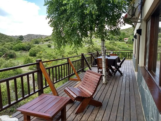 el mobiliario es de madera deck con vista a las sierras con mesas y sillas