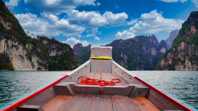 Barco tradicional navegando entre paisajes tropicales de Tailandia en un día soleado