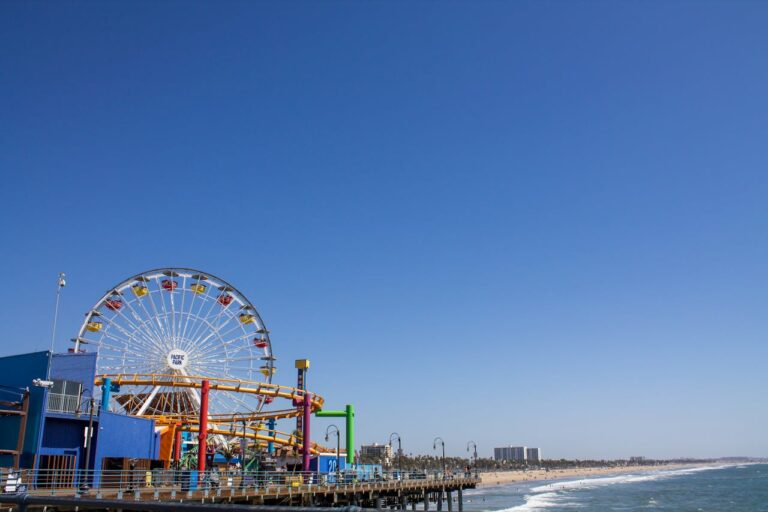 Rueda de la fortuna en el muelle de Santa Mónica, California, con vista al mar y cielo despejado.
