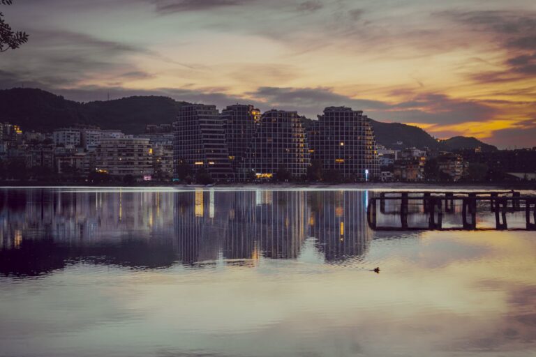 Atardecer en Vlorë, Albania, con edificios modernos reflejados en el mar.