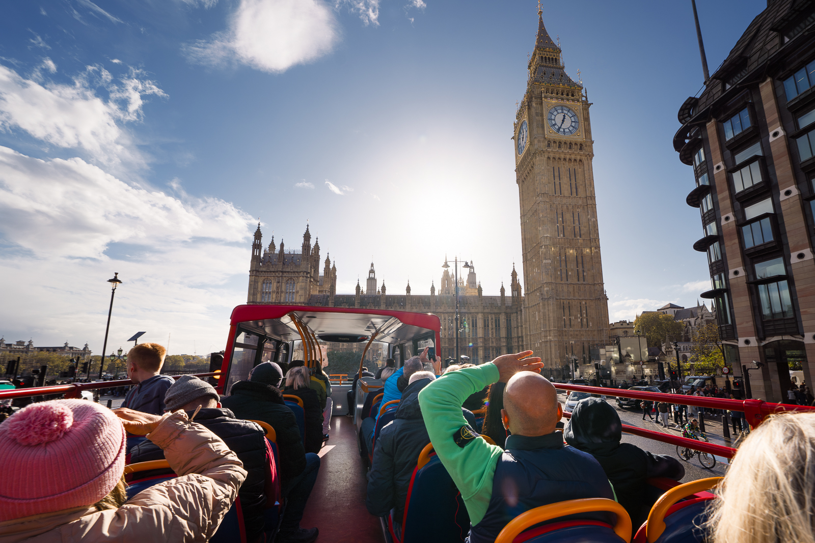 Autobús turístico City Sightseeing London de dos pisos, con diseño colorido, frente al Big Ben en Londres.