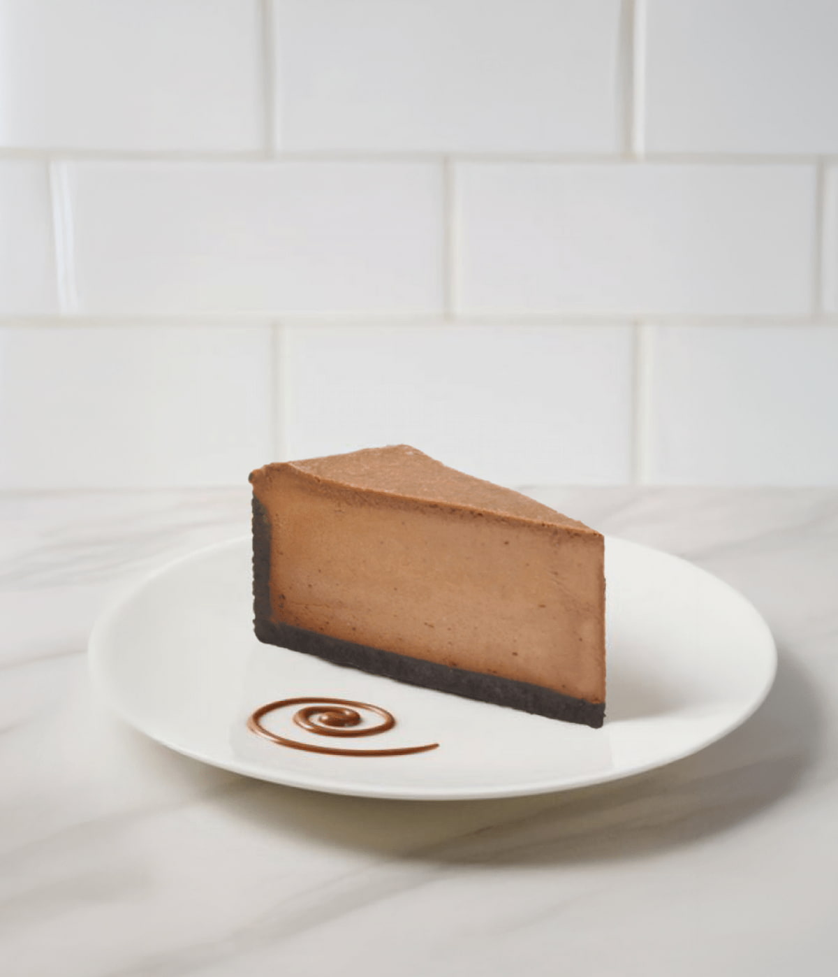Porción de cheesecake de chocolate sobre plato blanco con decoración de salsa.