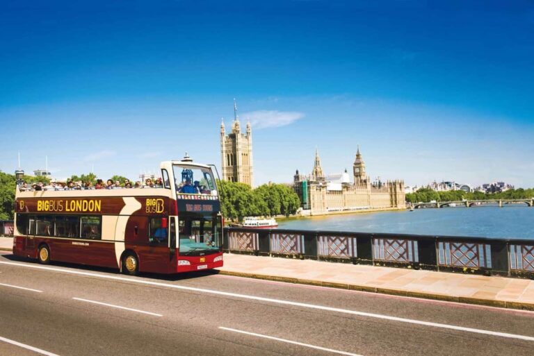 Autobús turístico Big Bus London circulando junto al río Támesis con el Parlamento y el Big Ben de fondo.