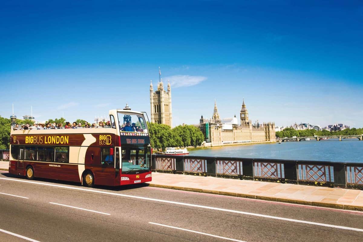 Autobús turístico Big Bus London circulando junto al río Támesis con el Parlamento y el Big Ben de fondo.