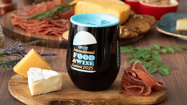 Vaso del EPCOT International Food & Wine Festival 2025 junto a tabla de quesos y fiambres. Vaso oficial del EPCOT International Food & Wine Festival 2025 sobre una tabla de quesos y embutidos.