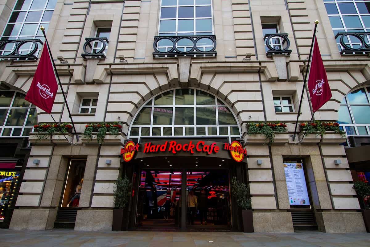 Entrada principal del Hard Rock Cafe en Londres, con sus características banderas burdeos y luces interiores llamativas.