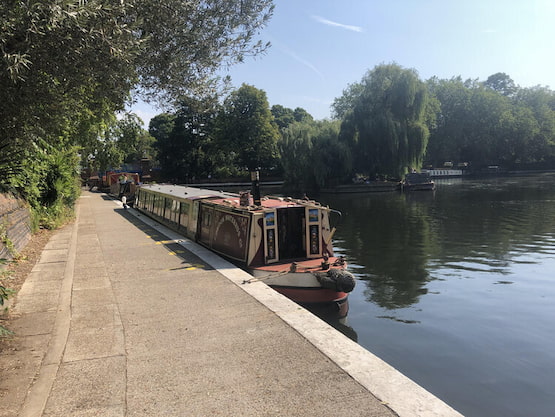 Narrowboat en Little Venice, un paseo diferente para descubrir Londres desde sus canales. Barco estilo narrowboat estacionado en los canales de Londres, rodeado de árboles y vegetación.