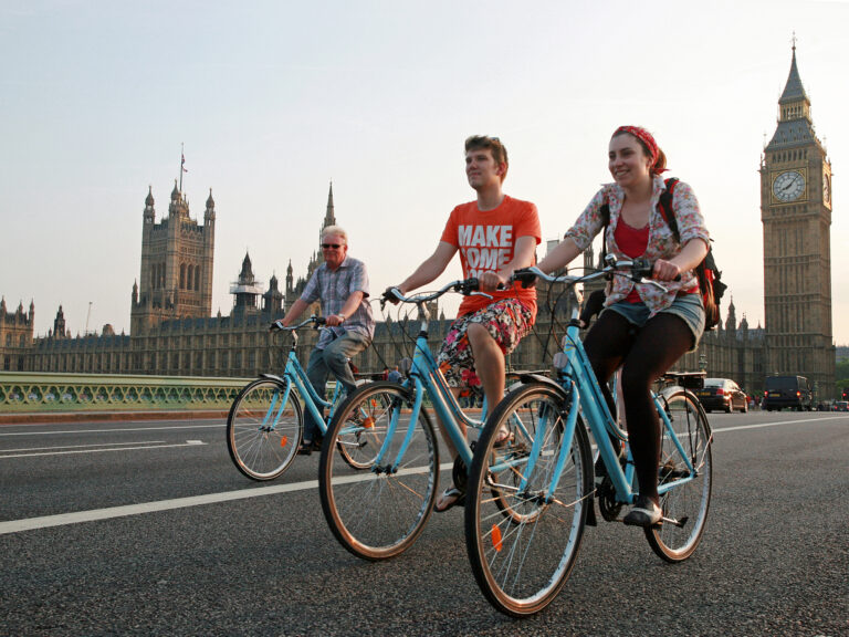 Turistas paseando en bicicleta por Westminster Bridge, con el Big Ben y el Parlamento de fondo en Londres.