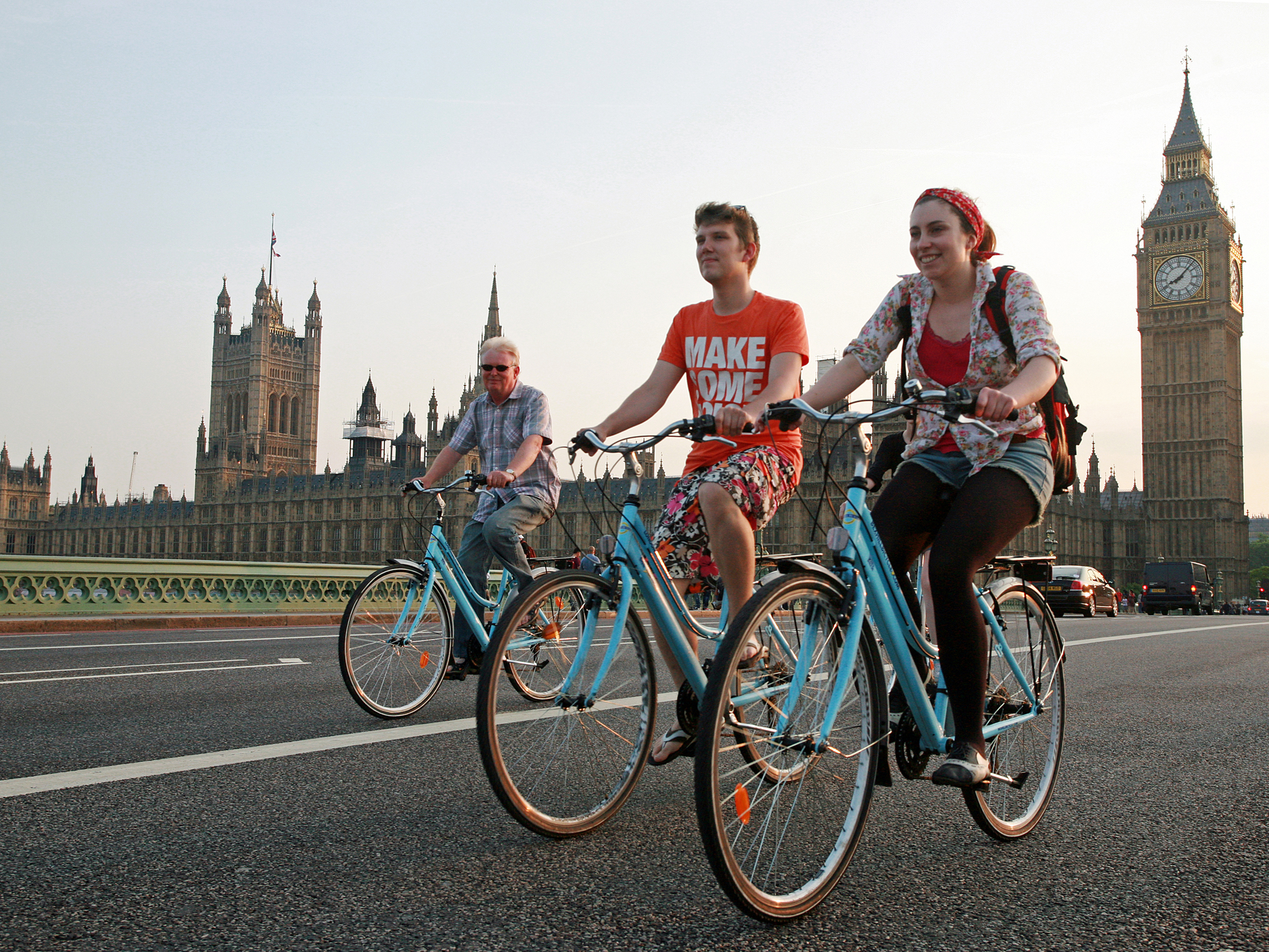 Turistas paseando en bicicleta por Westminster Bridge, con el Big Ben y el Parlamento de fondo en Londres.