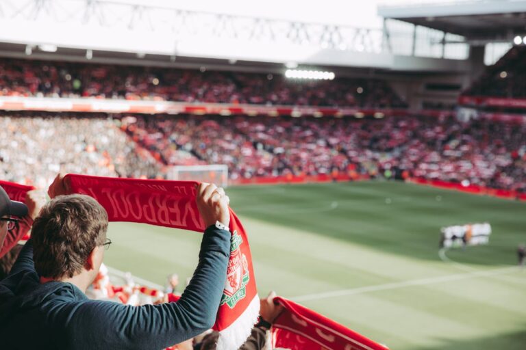 Aficionado del Liverpool levantando su bufanda en Anfield durante un partido.
