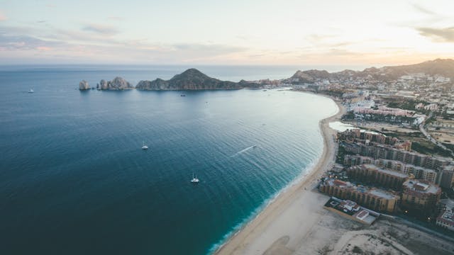 Cabo San Lucas, uno de los destinos más visitados en México. Vista aérea de la playa de Cabo San Lucas en Baja California Sur, México, con barcos y formaciones rocosas al fondo.
