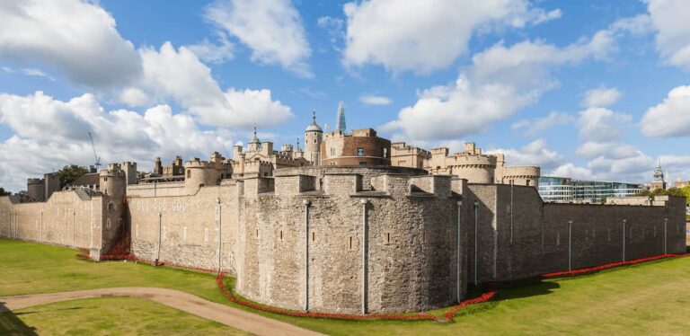 Murallas de la Torre de Londres con cielo azul y nubes, vista panorámica desde el exterior.
